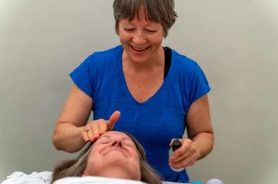 Massage therapist in a blue top performing a treatment on a client lying on a table